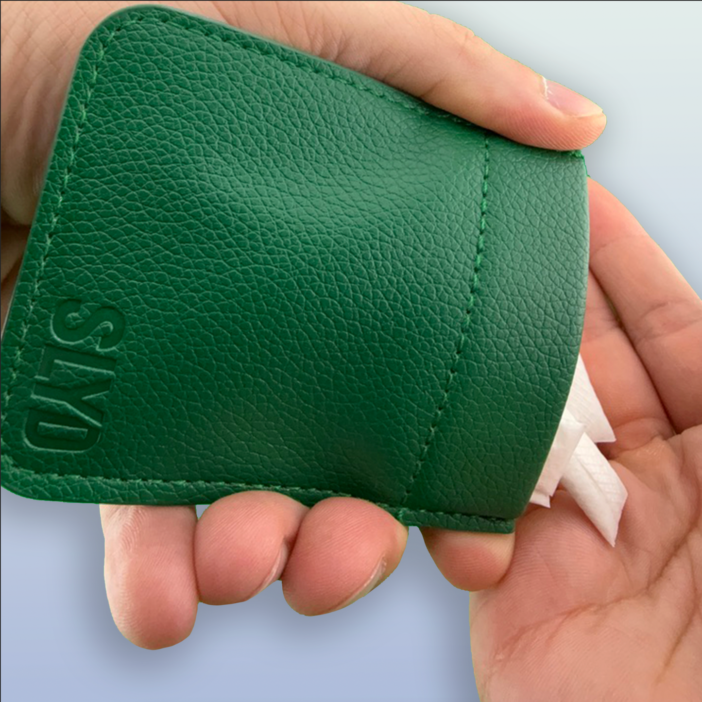 Green leather wallet held by a hand with a light gray background