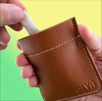 Brown leather wallet with 'SLYD' branding held by a hand against a gradient background